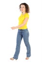 Woman in yellow shirt and jeans walking left