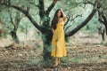 Woman in yellow summer linen dress in olive tree garden. Portrait of curly girl Royalty Free Stock Photo