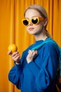 Woman in yellow sunglasses and blue sweater with lemons in net bag Royalty Free Stock Photo