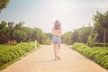 A woman in a yellow swimsuit and denim shorts and hat is on the path from the back Royalty Free Stock Photo