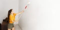 A woman in a yellow T-shirt is painting a wall in her house. A girl with a roller in her hand Royalty Free Stock Photo