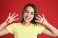 Woman in yellow t-shirt showing number eight with her hands on red background Royalty Free Stock Photo