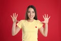 Woman in yellow t-shirt showing number ten with her hands on red background Royalty Free Stock Photo