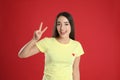 Woman in yellow t-shirt showing number two with her hand on red background Royalty Free Stock Photo