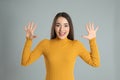 Woman in yellow turtleneck sweater showing number ten with her hands on grey background Royalty Free Stock Photo