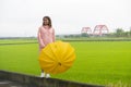 Woman with yellow umbrella standing with with rice filed and red red bridge at yuli Hualien Taiwan background
