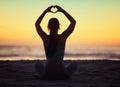 Woman yoga, heart hand and shadow at sunset at beach and ocean with peace and zen hands sign. Silhouette, nature and sea Royalty Free Stock Photo