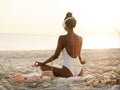 Woman in Yoga Meditation Pose with Headphones on the Beach