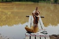 A woman yogi sits with her back to the riverbank on a bridge and meditates on relaxing her body in nature