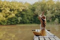 A woman yogi sits with her back to the riverbank on a bridge and meditates on relaxing her body in nature