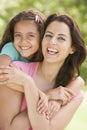 Woman and young girl embracing outdoors smiling