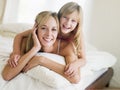 Woman and young girl lying in bed smiling Royalty Free Stock Photo