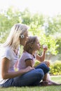 Woman and young girl outdoors blowing bubbles Royalty Free Stock Photo