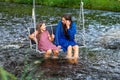 a woman and a young girl are swinging across a fast-flowing river, laughing and splashing with water Royalty Free Stock Photo