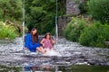 a woman and a young girl are swinging across a fast-flowing river, laughing and splashing with water Royalty Free Stock Photo