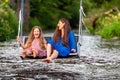 a woman and a young girl are swinging across a fast-flowing river, laughing and splashing with water Royalty Free Stock Photo