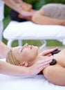 Woman, zen and hot stone massage with hands of masseuse at spa, healing with holistic treatment. Rocks on shoulders Royalty Free Stock Photo