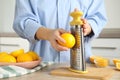 Woman zesting lemon at table indoors, closeup