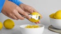 Woman zesting lemon at white marble table, closeup