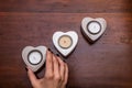 Womand hand and heart shaped candles on wooden desk