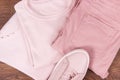 Womanly pink leather shoes, cotton pants and sweater on rustic boards