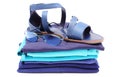 Womanly sandals and sunglasses on pile of blue clothes. White background Royalty Free Stock Photo
