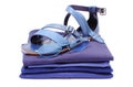 Womanly sandals and sunglasses on pile of blue clothes. White background Royalty Free Stock Photo