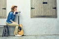 Womann sitting on bench with guitar.