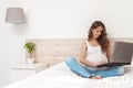 The womanPortrait of a beautiful pregnant long haired smiling woman sitting with crossed  working by the laptop and choosing color Royalty Free Stock Photo