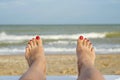 Womans feet on the beach. Female legs and feets with red nails on sunbed on the beach. Summer relaxation on sea background Royalty Free Stock Photo