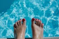 womans feet with red nail polish on pool deck, toes curling Royalty Free Stock Photo