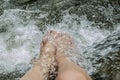 Womans feet refreshing under clear and cool water. Royalty Free Stock Photo