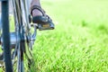 Womans foot on bicycle pedal on green grass closeup Royalty Free Stock Photo