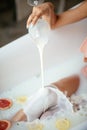 Closeup view of womans hand pouring glass of milk into bathtub. Royalty Free Stock Photo