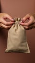 A womans hand grips a subsidy themed canvas bag on beige