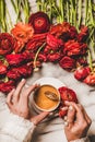 Womans hand holding cup of black coffee over red flowers Royalty Free Stock Photo