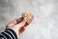 Womans hand holding ginger bread heart cookie with white icing. Valentine or Mothers day holiday day composition. Love