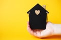 Womans hand holding little toy house made of chalk board on a orange background Royalty Free Stock Photo