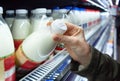 Womans hand holding milk bottle in supermarket. Man shopping milk in grocery store. Man checks product expiration date before buyi Royalty Free Stock Photo