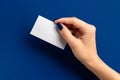 Womans hand holding paper card on blue background Royalty Free Stock Photo