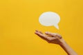 Womans Hand Holding Speech Bubble on Yellow Background Royalty Free Stock Photo