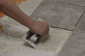 womans hand laying down thinset to tile a floor