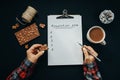 Womans hand with pencil and Blank album paper with New Year Resolution inscription, chocolate, cocoa, cone on black background, t Royalty Free Stock Photo