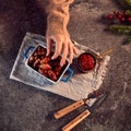 Womans Hand Reaches For Dish Of Traditional Christmas Pigs In Blankets On Table Set For Meal