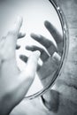 Womans hand reflected in round mirror