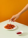 Womans hand takes sweet potato fries on green table. Vegan alternative food recipe.