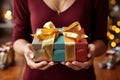 A womans hands hold a colorful gift box with a ribbon