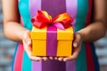 A womans hands hold a gift box with a ribbon
