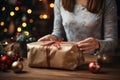 Womans hands holding a box with Christmas present. Wrapping Christmas gifts on Christmas eve. Using craft paper for packaging.