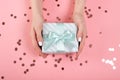 Womans hands holding gift or present box decorated confetti on pink pastel table top view. Flat lay composition for birthday or Royalty Free Stock Photo